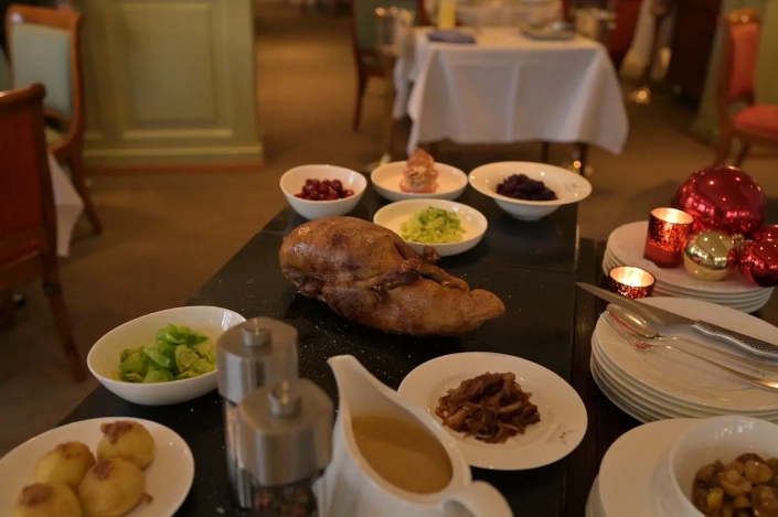 Ein festlich gedeckter Tisch mit einem saftigen Hähnchen als Mittelpunkt, begleitet von verschiedenen Beilagen wie Kartoffeln, Gemüse und Soße, warm beleuchtet durch Kerzenlicht im Restaurant Scherrer, schafft eine gemütliche und - Ihr Landhaus Scherrer aus Hamburg