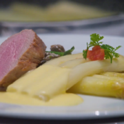 Perfekt gegartes Medium-Rare-Steak mit zartem Spargel und einer cremigen Sauce Hollandaise, garniert mit einer Kirschtomate und Petersilie für einen Hauch von Farbe und Frische. - Ihr Landhaus Scherrer aus Hamburg