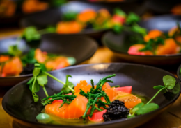 Elegante Teller mit geräuchertem Lachs, geschmückt mit frischem Grün, Seetang und einer Garnitur aus Kaviar, bereit zum Servieren bei einem Gourmet-Event. - Ihr Landhaus Scherrer aus Hamburg